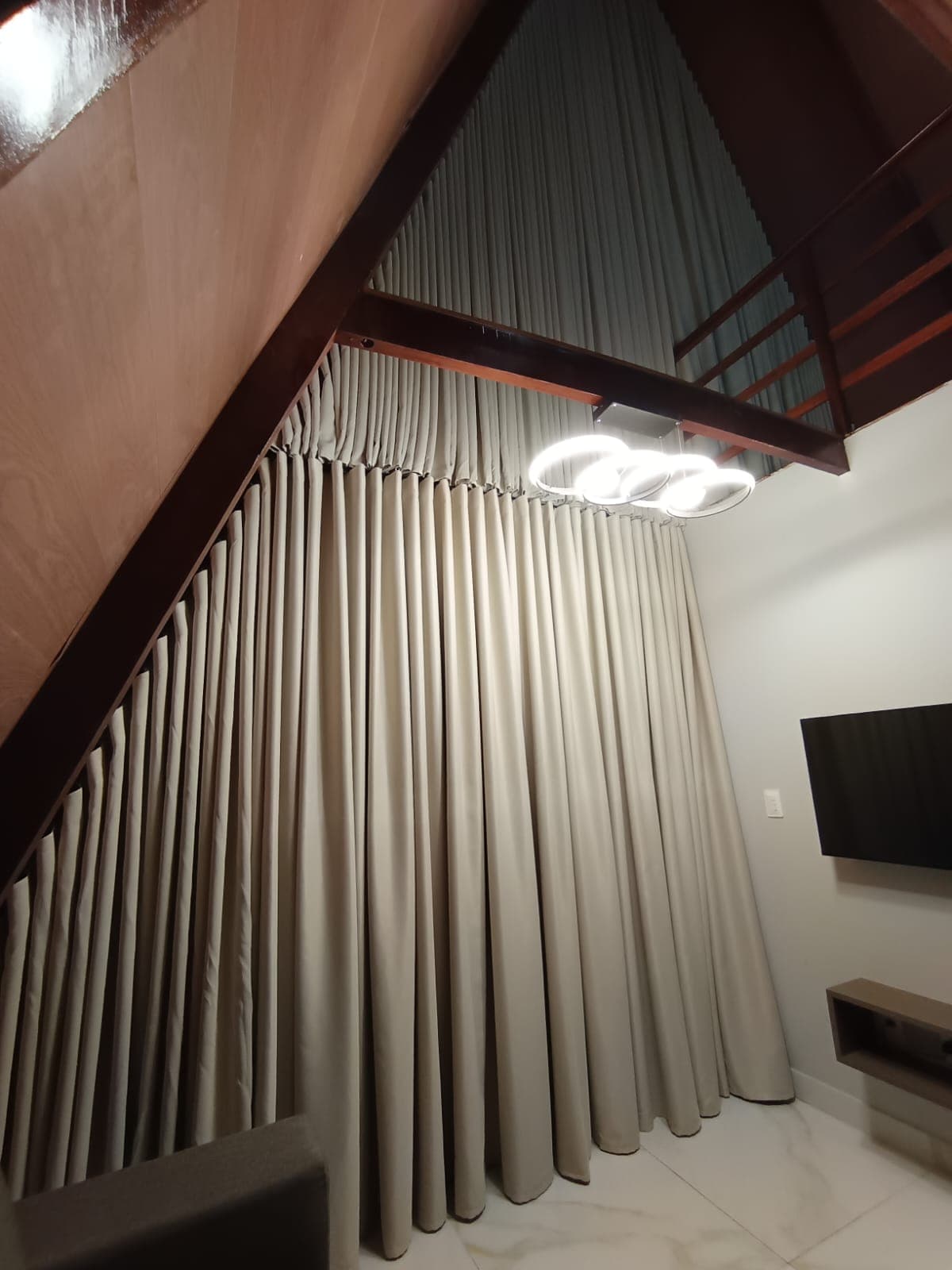 Cortinas do piso ao teto em ambiente com pé-direito duplo, mezanino e lustre